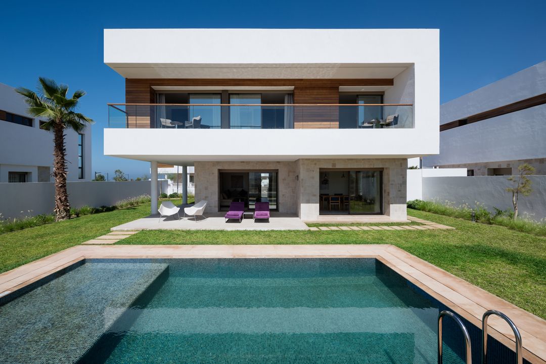 A modern two-story house with a swimming pool, outdoor seating, and a balcony.