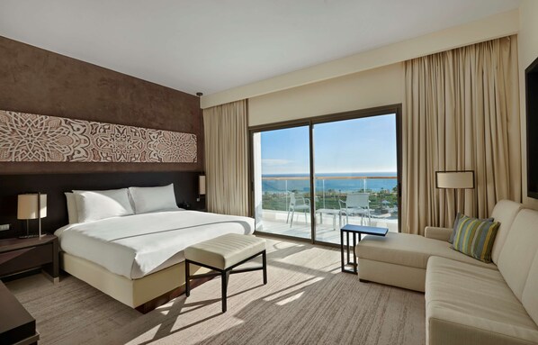 A hotel room with a large bed, a sofa, a small table, and a view of the ocean. - Hyatt Place Taghazout Bay (Taghazout)