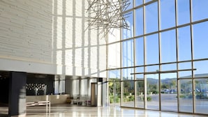 Un vestíbulo amplio con un diseño de techo moderno, ventanas grandes que ofrecen vistas al exterior y un suelo reflectante.