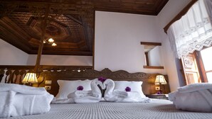 A hotel room with a wooden ceiling, a large bed with white linens, and two bedside lamps. - Kalemi Hotel (Gjirokastër)