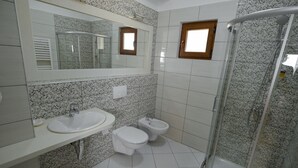 A bathroom with a sink, toilet, bidet, and a glass-enclosed shower. - Kalemi Hotel (Gjirokastër)