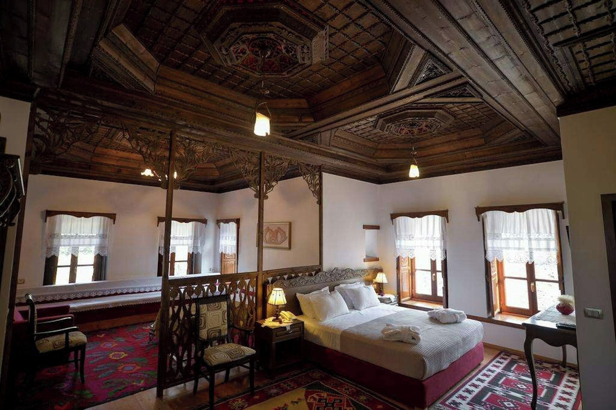 A traditional room with a large bed, wooden ceiling, and patterned rugs.