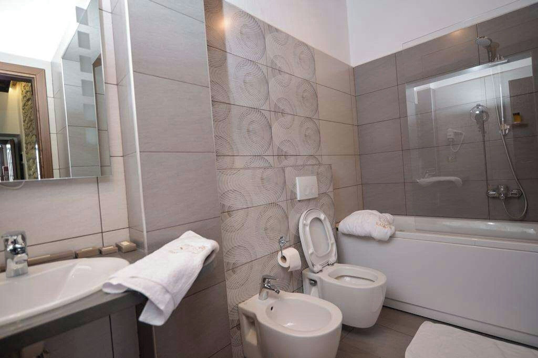 A modern bathroom with a bathtub, toilet, bidet, and sink.