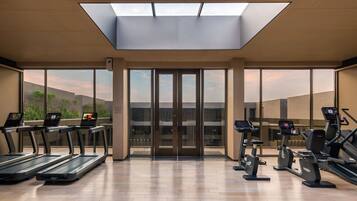 Un gimnasio moderno con cintas de correr, elípticas y una claraboya.