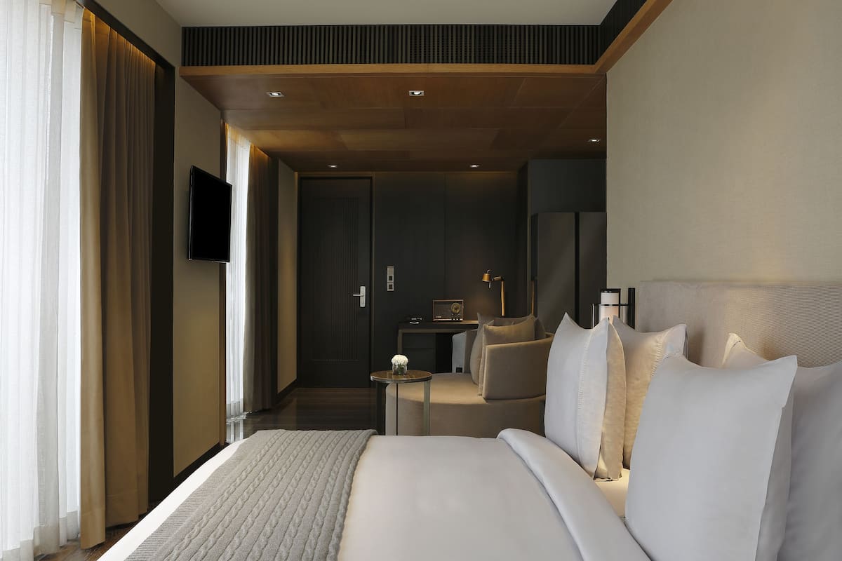 A modern hotel room with a large bed, a desk, and a television.