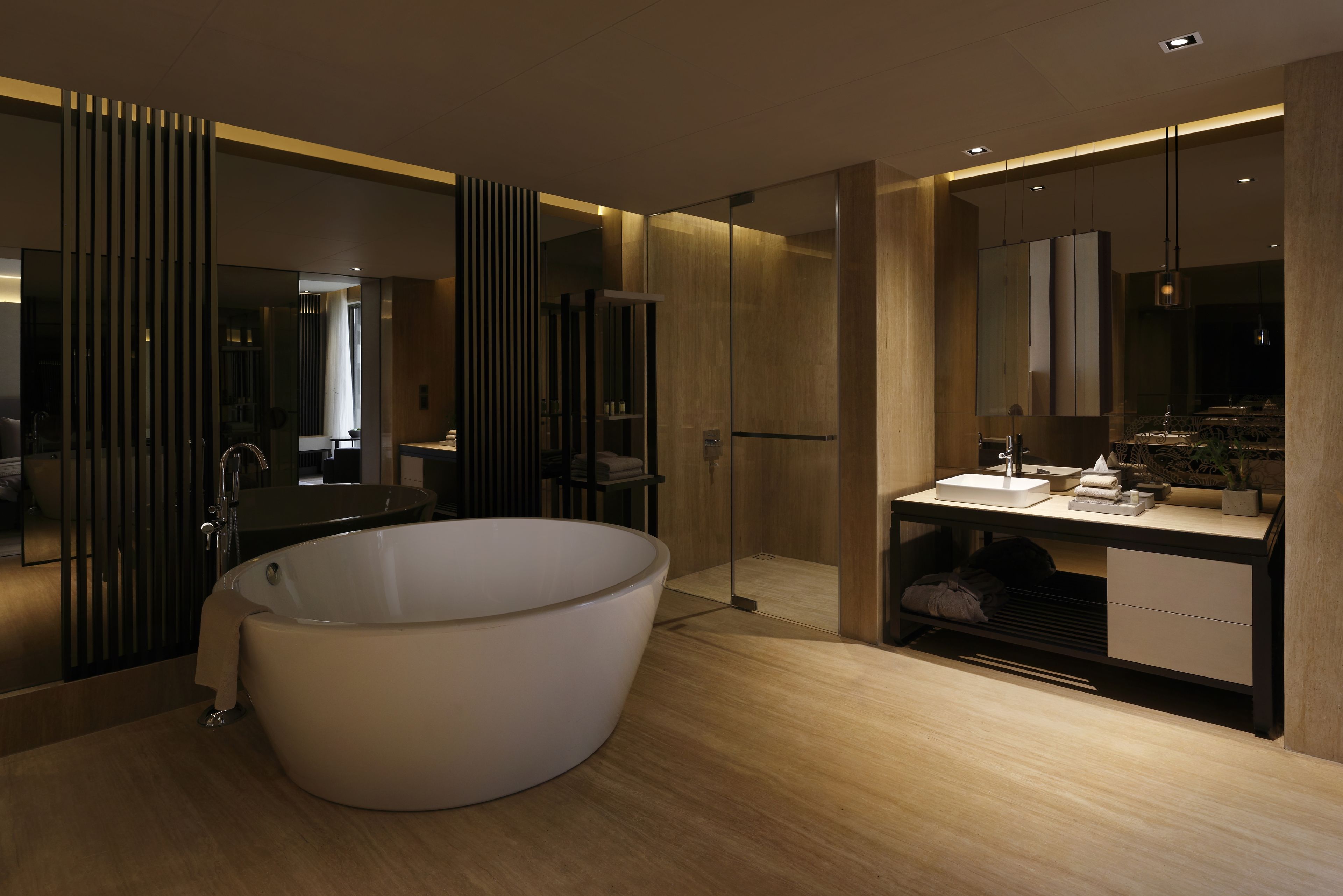Un baño moderno con una bañera independiente, un tocador con espejo y un espejo grande sobre el lavabo.