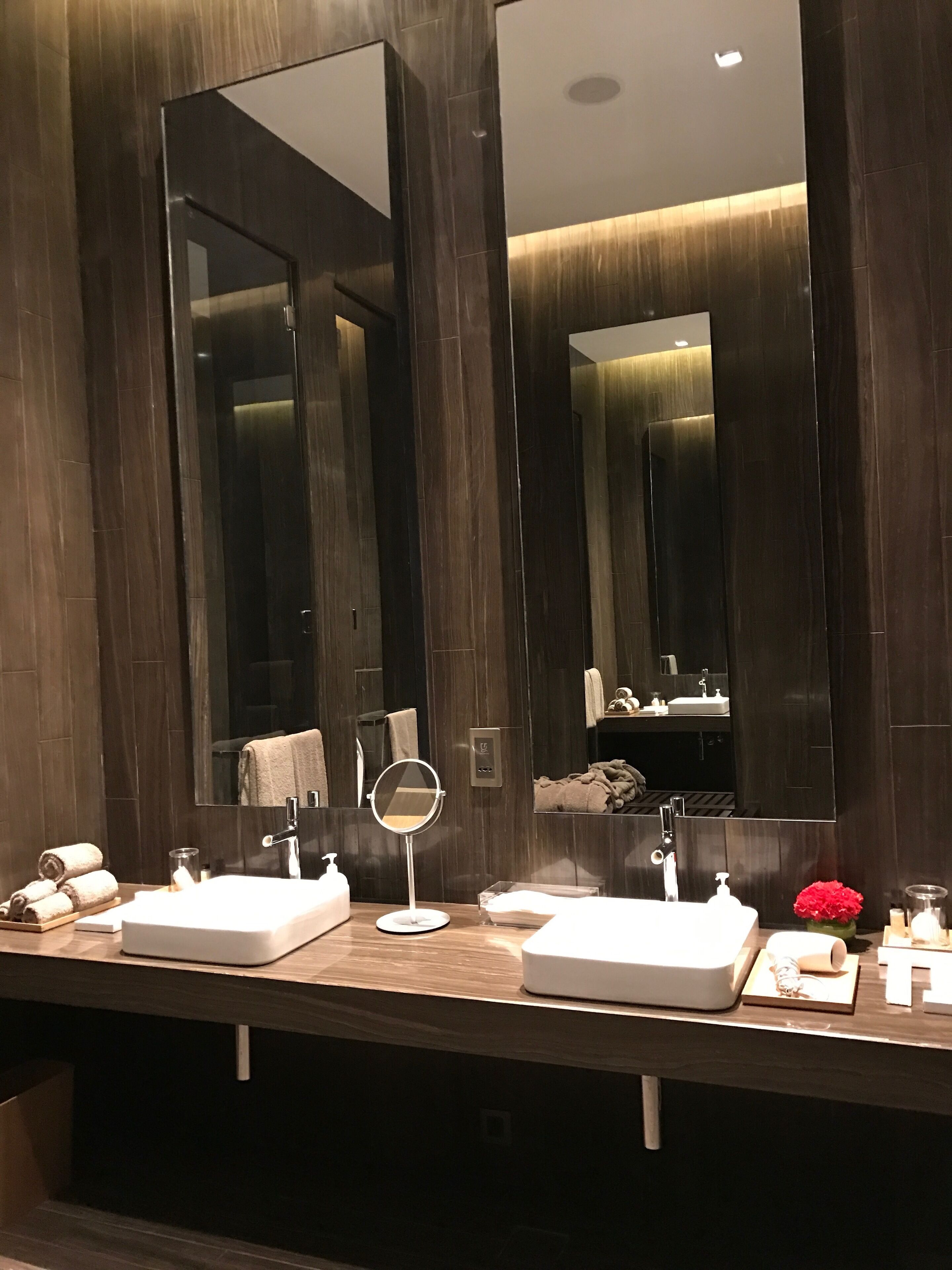 A modern bathroom with two sinks, a round mirror, and a large mirror above the sinks.