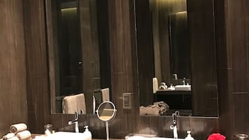 A modern bathroom with two sinks, a round mirror, and a large mirror above the sinks.