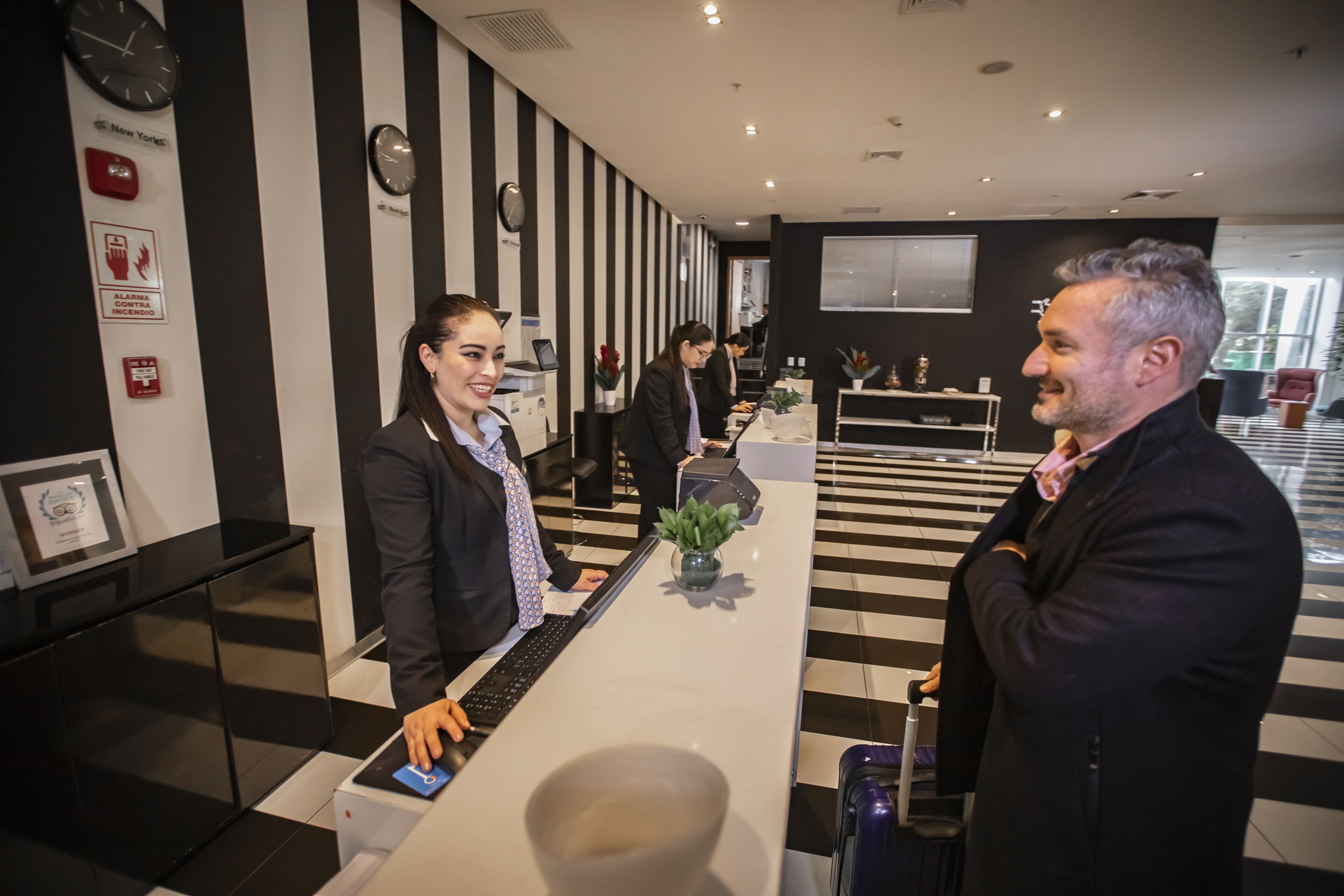 A reception area with a check-in counter, black and white striped walls, and a clock on the wall.
