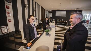 A reception area with a check-in counter, black and white striped walls, and a clock on the wall.