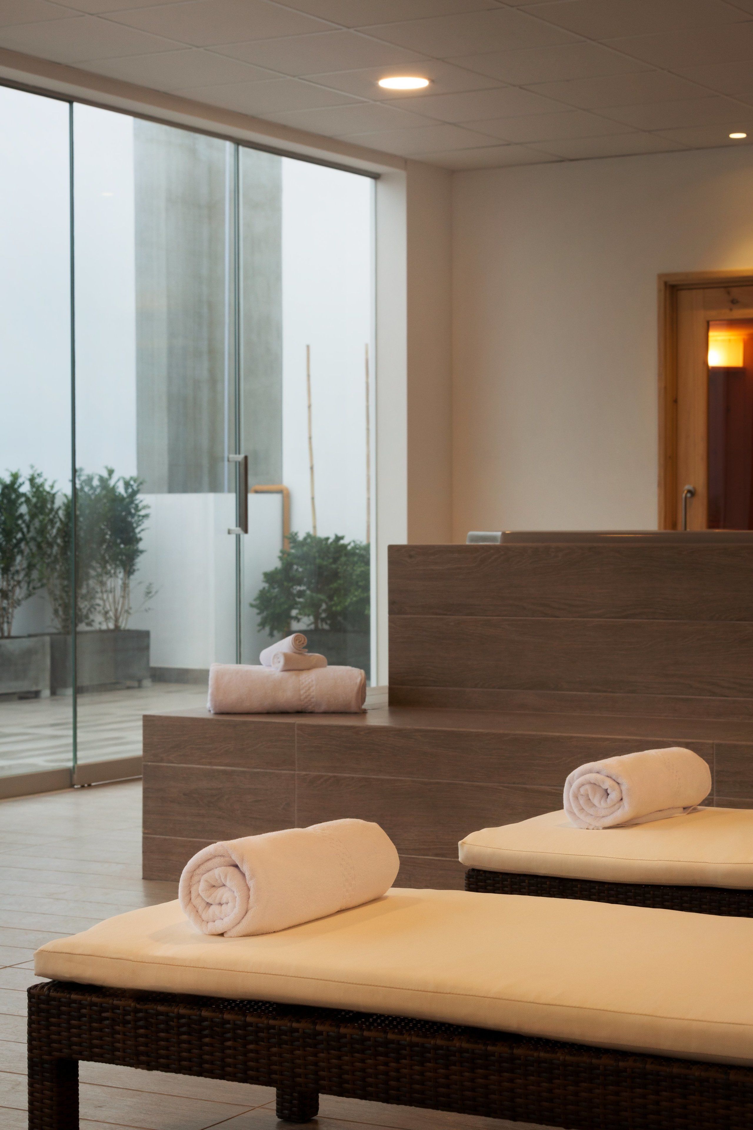 A spa area with two massage chairs, a glass wall, and a wooden reception desk.
