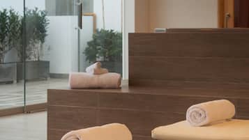 Un área de spa con dos sillas de masaje, un muro de cristal y un mostrador de recepción de madera.