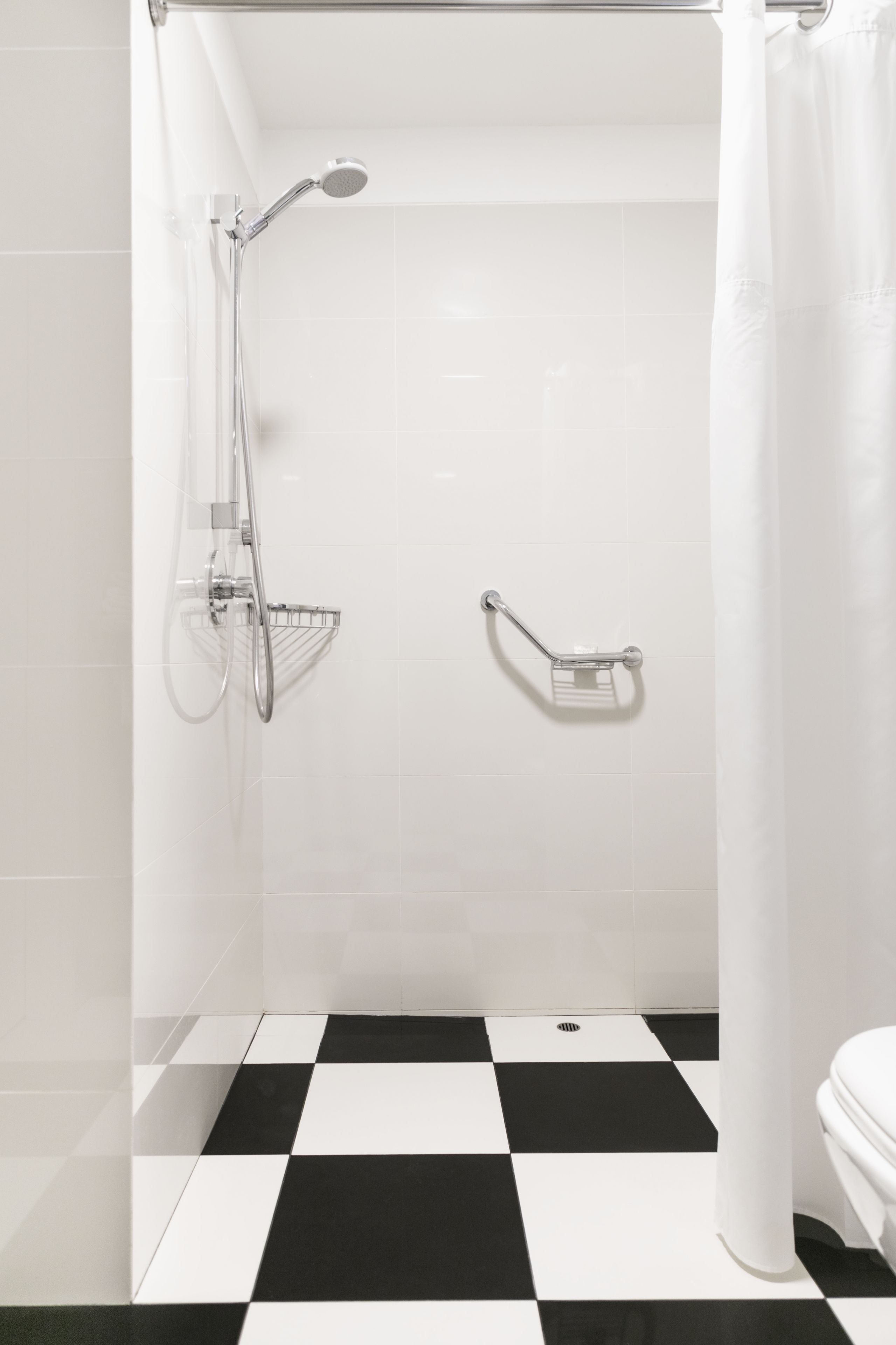 A bathroom with a shower, a toilet, and a checkered floor.