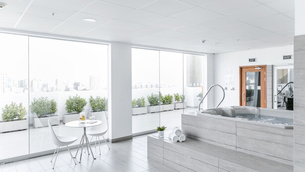 Una cocina moderna con un lavamanos, una puerta de madera y vistas a la ciudad a través de amplios ventanales.
