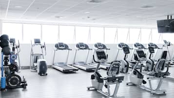 Un gimnasio con cintas de correr, elípticas y equipo de levantamiento de pesas.