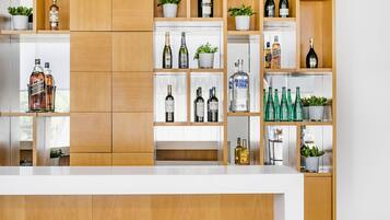 Una zona de bar moderna con estantes de madera que exhiben diversas botellas de alcohol y plantas en macetas.