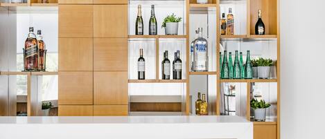 A modern bar area with wooden shelves displaying various bottles of alcohol and potted plants.