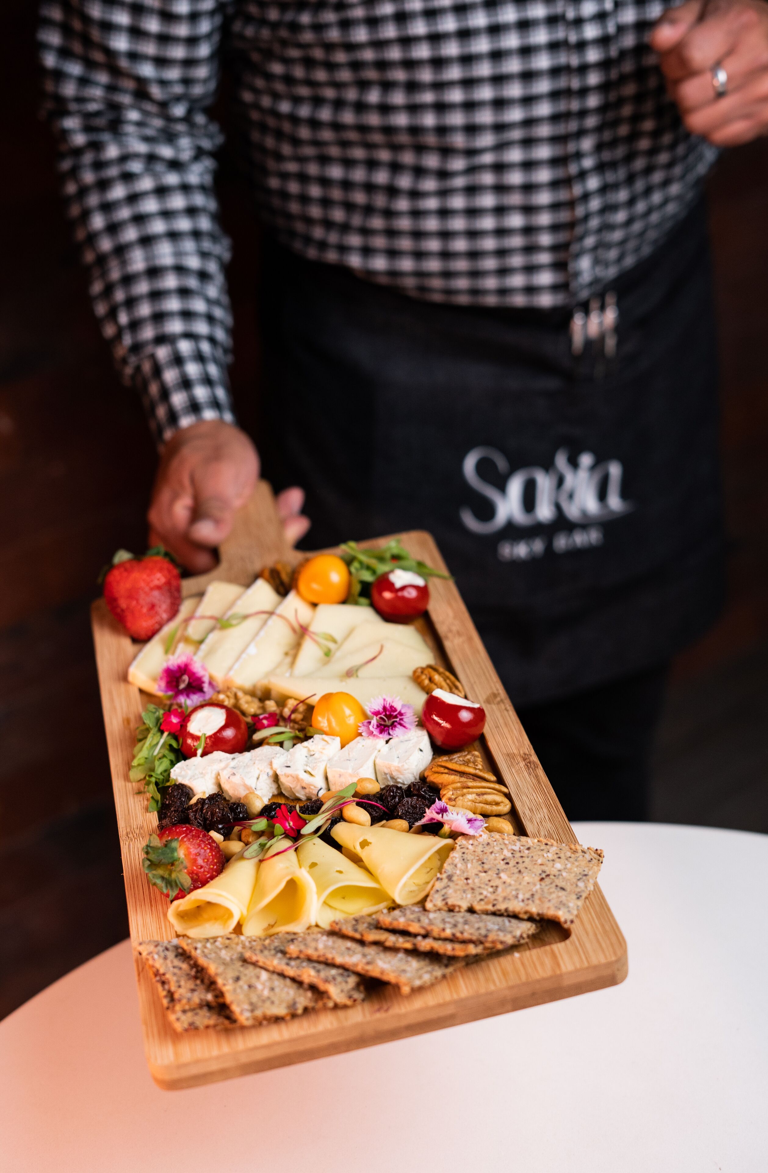 Una tabla de madera con una variedad de quesos, frutas y galletas.