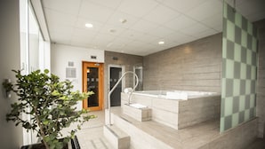 Un baño moderno con una bañera grande, una planta en maceta y una escalera que lleva a la zona de la ducha.