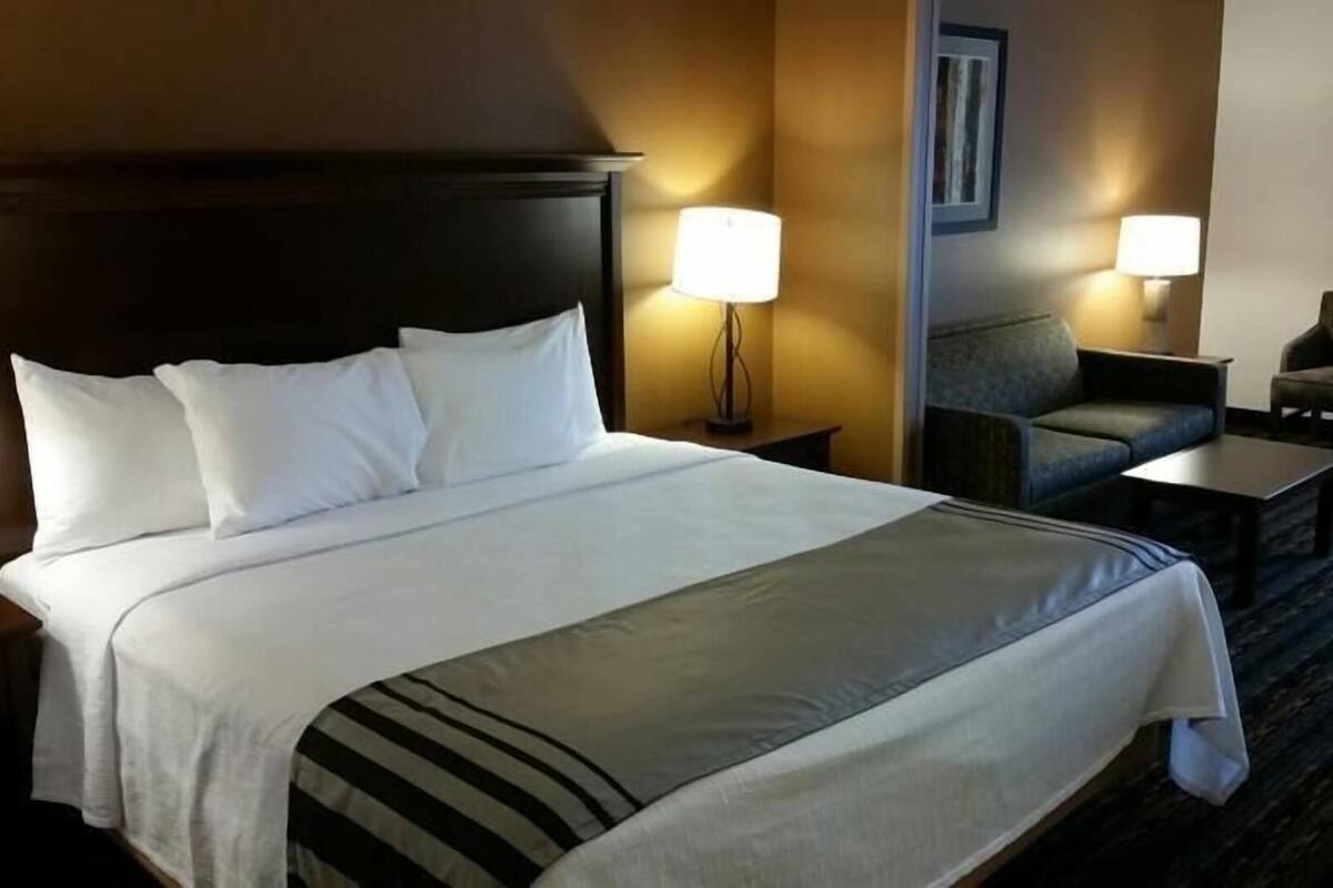 A hotel room with a large bed, two bedside tables, a desk, two chairs, and two lamps.