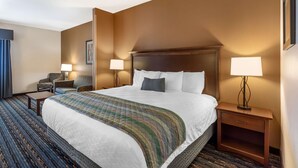 Een hotelkamer met een groot bed, twee bedlampen, een nachtkastje, een stoel en een vloerbedekking.