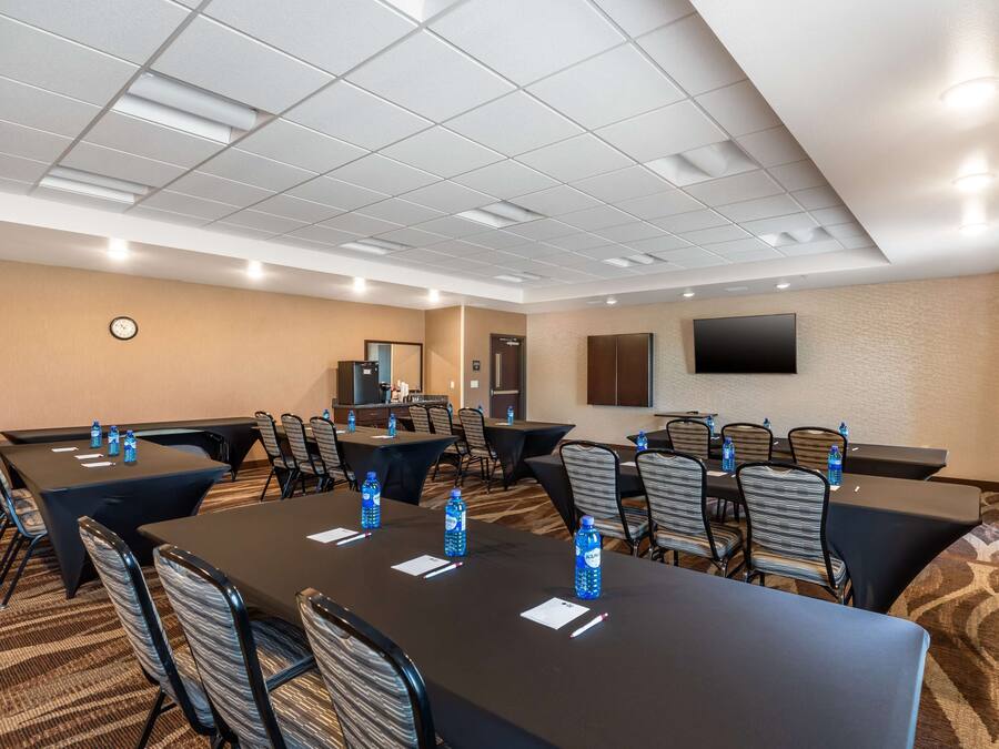 A conference room with multiple tables and chairs, equipped with water bottles and name cards.