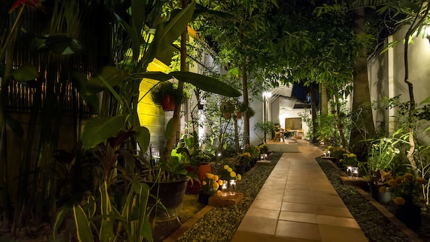 Ein stimmungsvoller Gartenpfad bei Nacht mit Topfpflanzen und Kerzen.