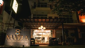 Entrada de hotel con un cartel que dice "NAVELA" y un área de estar al aire libre cubierta.