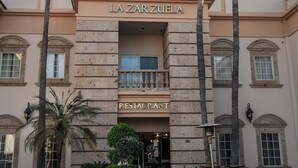 Un edificio con un letrero que dice "LA ZARZUELA RESTAURANT" y palmeras en primer plano.