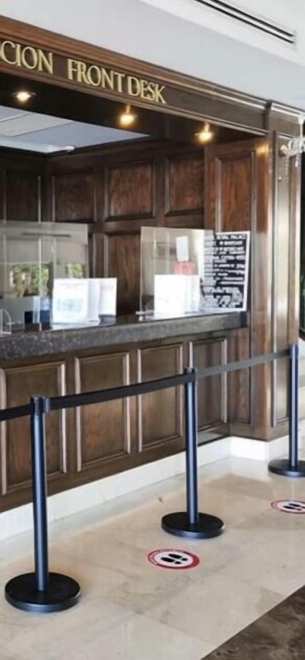 A reception desk area with a wooden panel design, a glass partition, and a sign above it. - Hotel Royal Palace (Hermosillo)