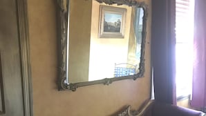 A room with a vintage sofa, a large ornate mirror, and a window with curtains. - Trade Winds Bed and Breakfast (Philadelphia)