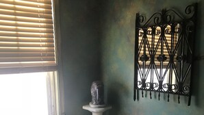 A small dining area with a round table, two chairs, a decorative stone sculpture, and a wrought iron gate. - Trade Winds Bed and Breakfast (Philadelphia)