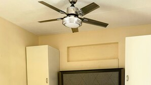 A bedroom with a bed, a ceiling fan, a wardrobe, and a nightstand. - Skyblue Beach Apartments (Villa)