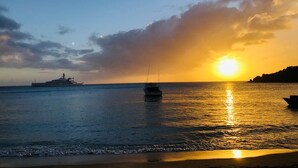 A sunset over a calm sea with boats, a yacht, and a distant coastline. - Skyblue Beach Apartments (Villa)