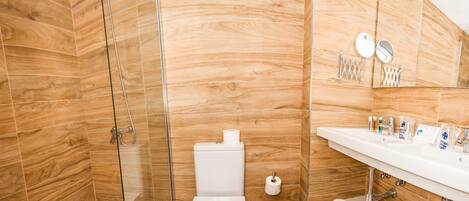 A bathroom with a wooden wall, a glass shower enclosure, a white toilet, and a sink with toiletries.