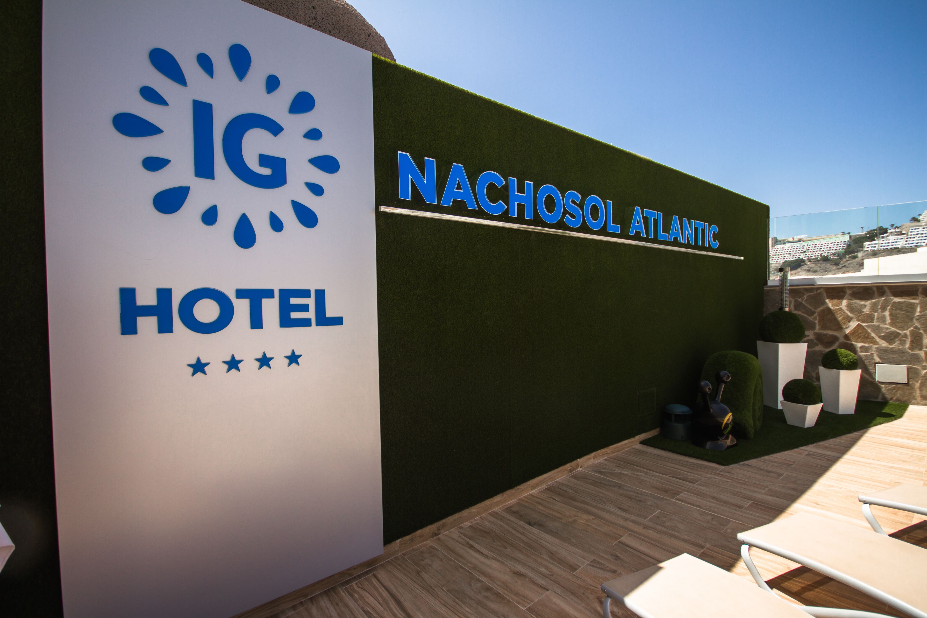 Segnaletica di un hotel con il nome 'NACHOSOL ATLANTIC' e un logo raffigurante un sole e delle gocce di pioggia.
