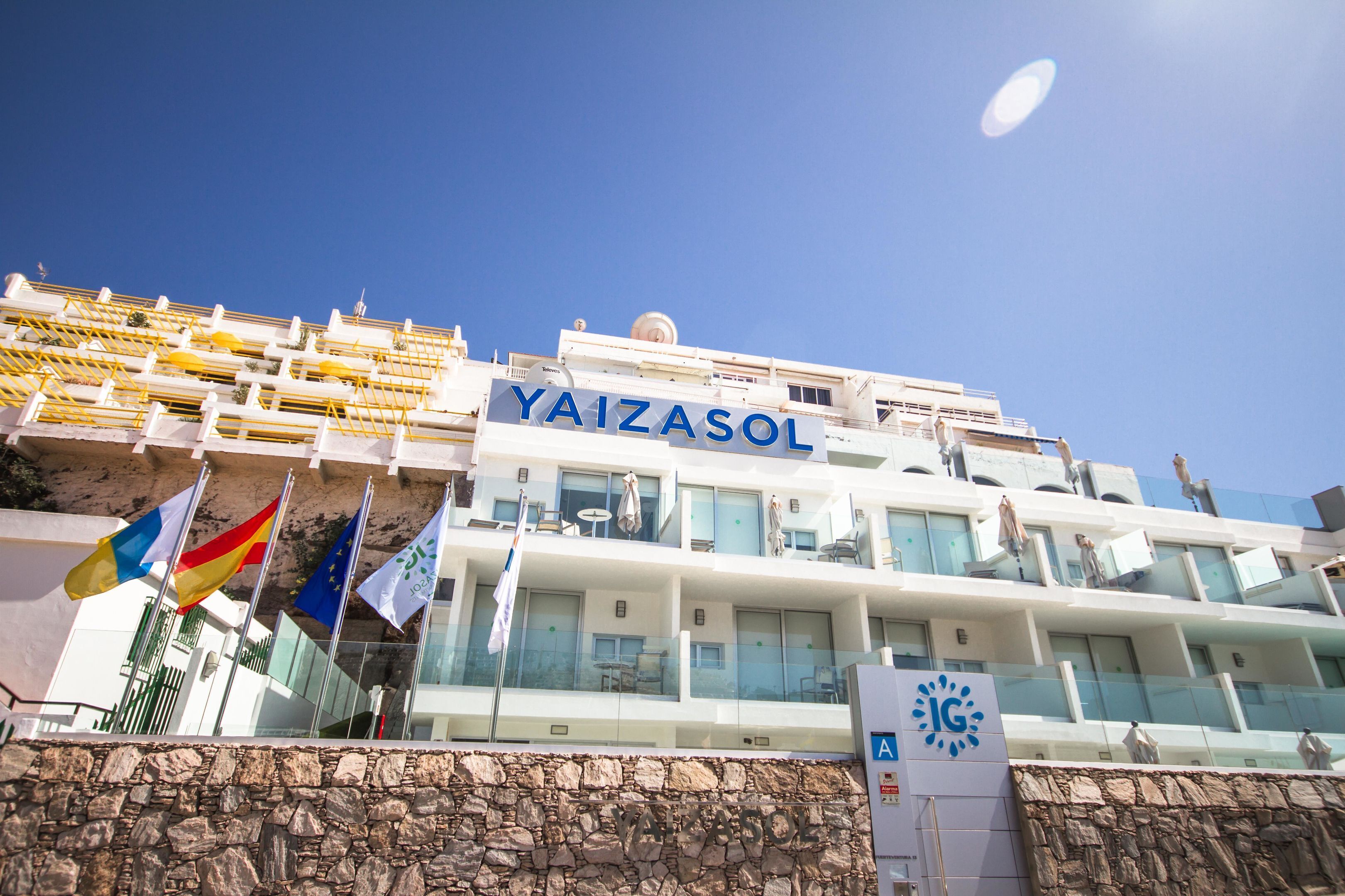 A building with the sign "YAIZASOL" and multiple flags.