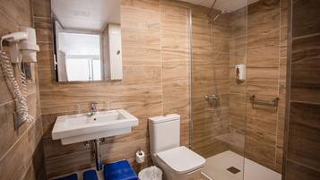 A bathroom with a sink, toilet, and glass-enclosed shower.