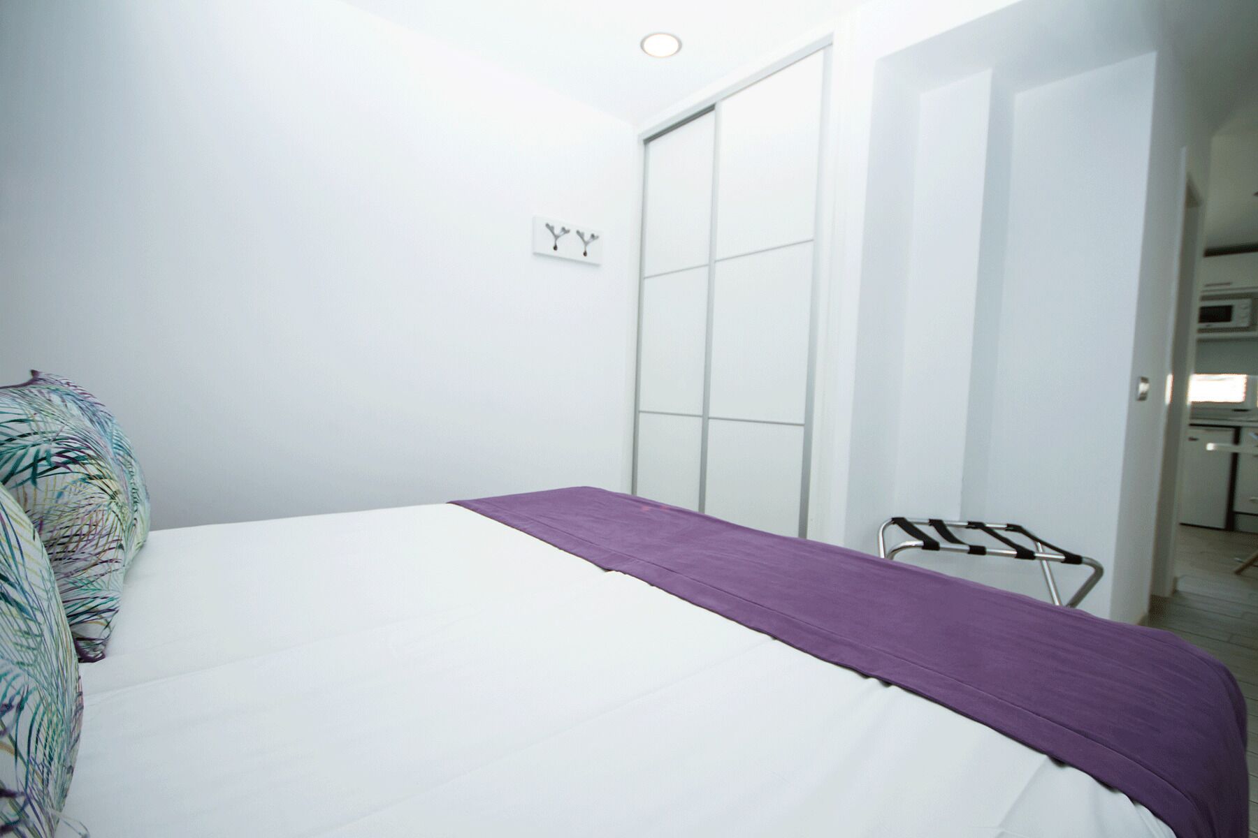 Un dormitorio con cama, armario y pequeña cocina.