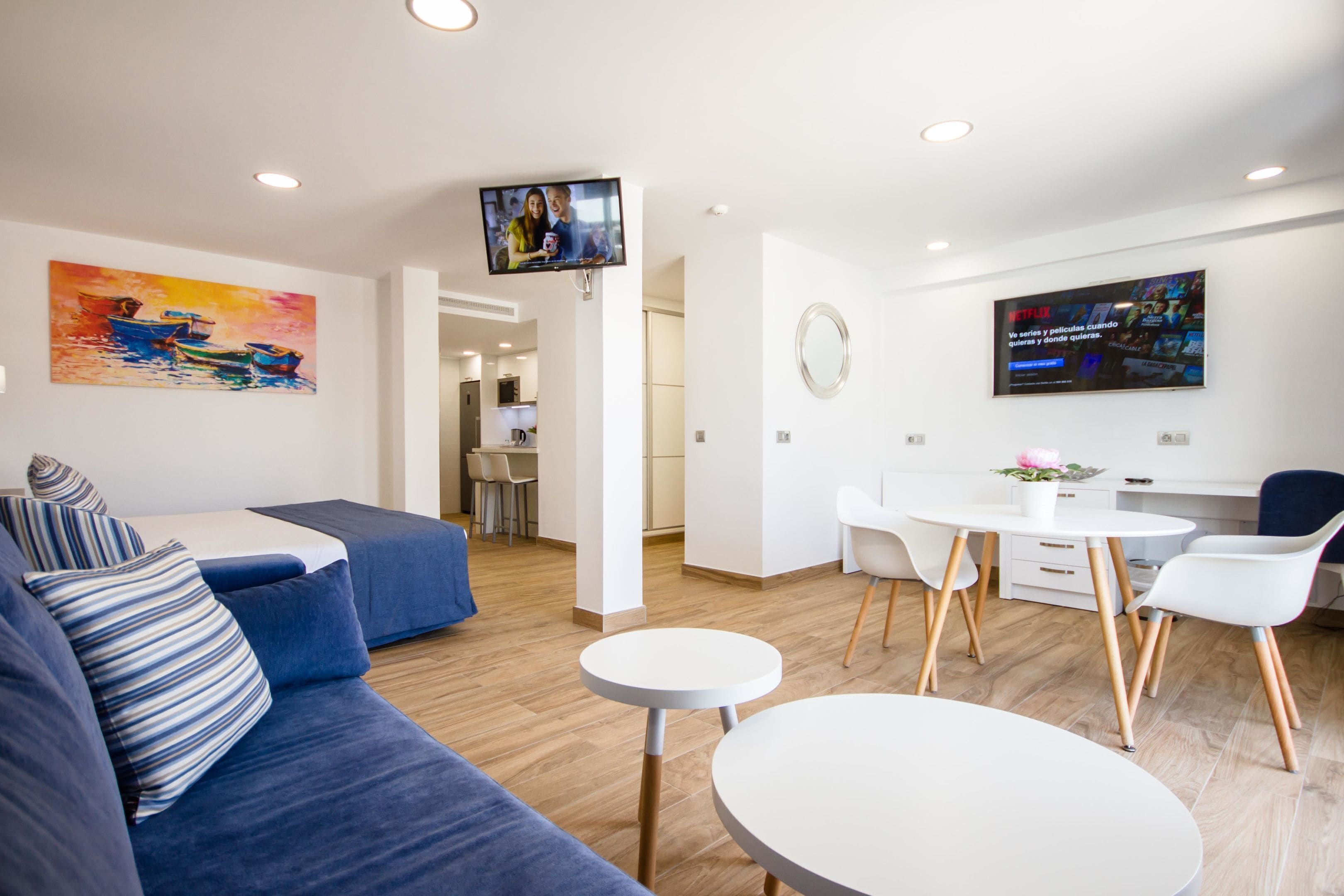 Una sala de estar moderna con un sofá, una mesa de comedor y un televisor montado en la pared.