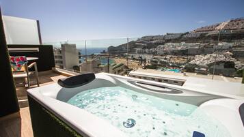 A hot tub with a clear view of a coastal town and beach.