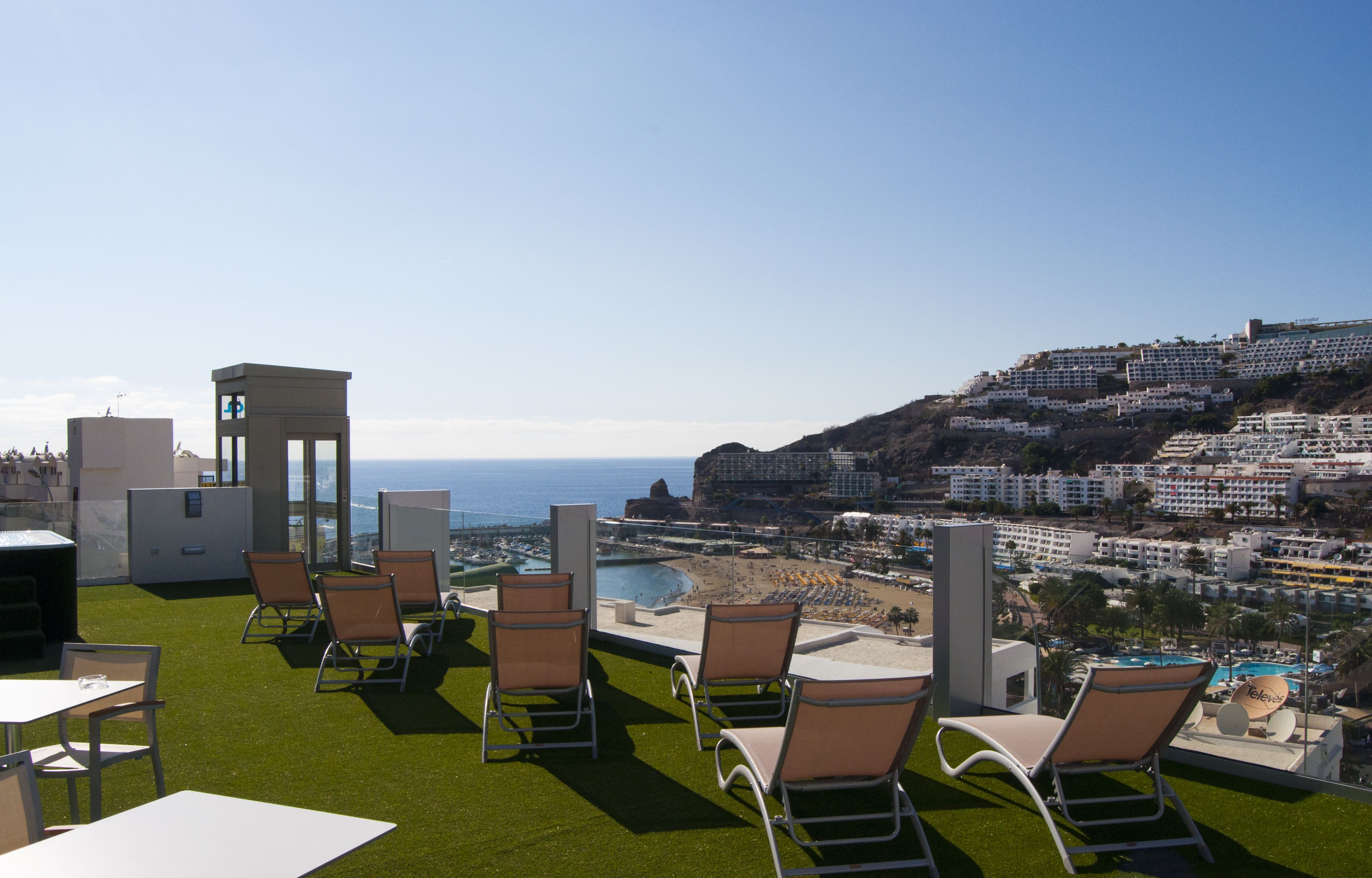 Eine Dachterrasse mit Sitzgelegenheiten im Freien, einem Pool und Blick auf Strand und Meer.