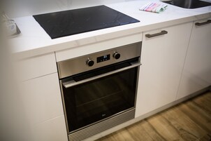 Una cucina moderna con forno integrato, orologio digitale e piano di lavoro in acciaio inossidabile.