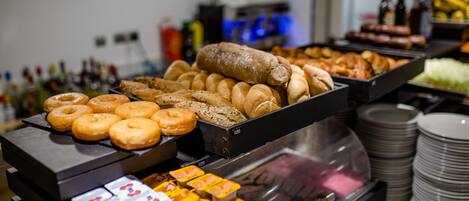 A buffet with various food items including donuts, pastries, and packaged snacks.