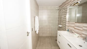 A modern bathroom with a large mirror, white vanity, and a shower area.