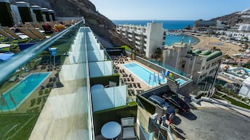 Un bar sul tetto con piscina, poltrone relax e vista sulla spiaggia e sull'oceano.