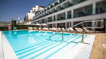 Een buitenzwembad en ligstoelen