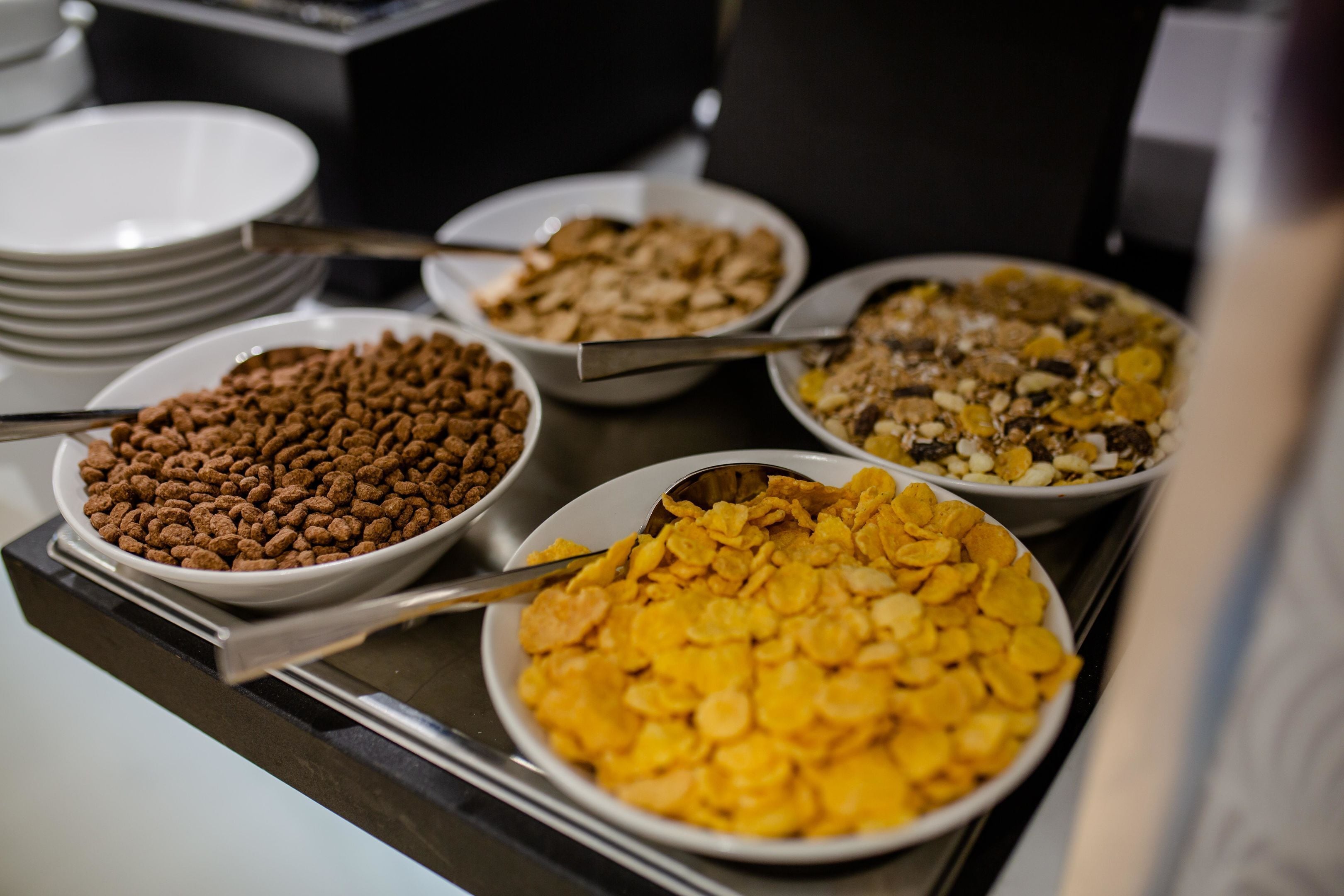 Une table de buffet avec différents bols de céréales et de noix.