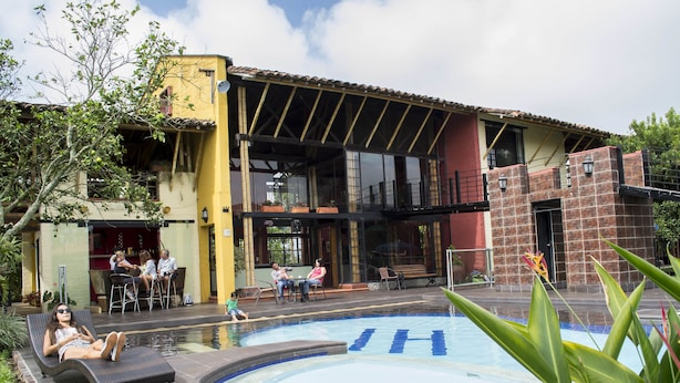 A pool area with lounge chairs and a bar area with people.