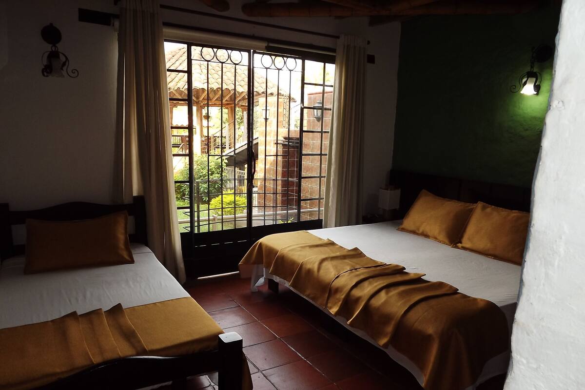 Ein Hotelzimmer mit zwei Betten, einem Fenster mit Gitter und Blick nach draußen.